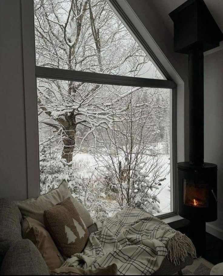 a living room filled with furniture and a large window covered in snow next to a fire place