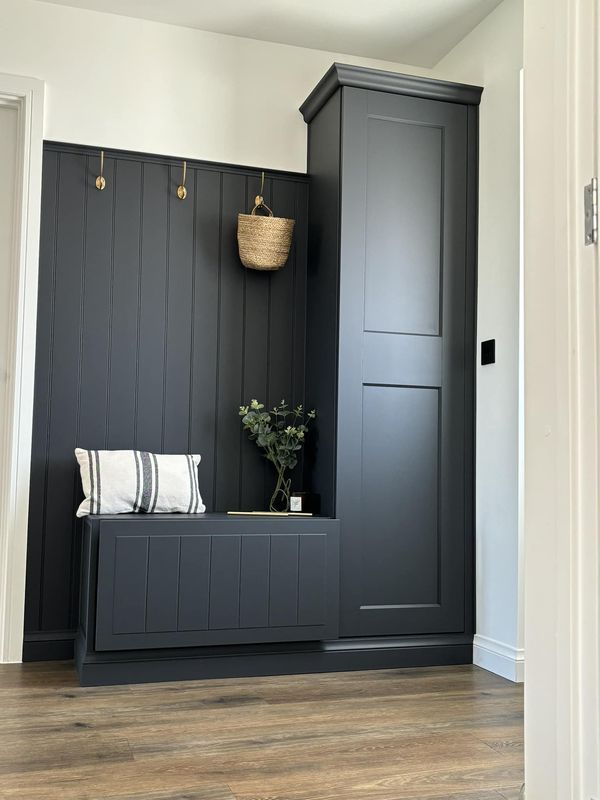 a room with black painted walls and wooden flooring, an entryway to the bedroom