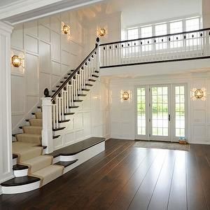 an empty room with wooden floors and white railings on the wall, along with stairs leading up to two sets of windows