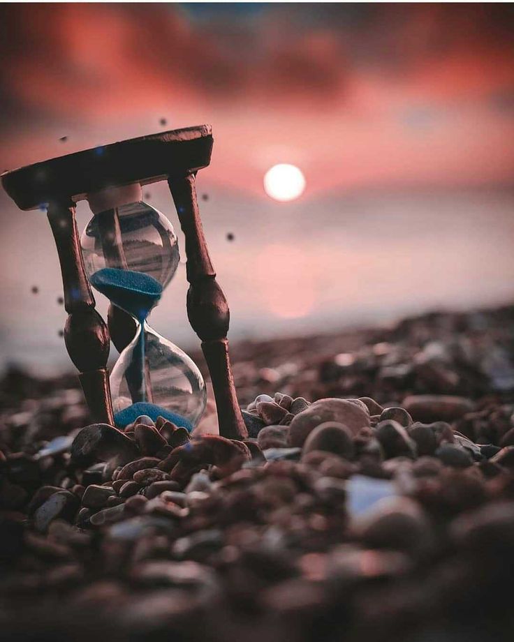 an hourglass sitting on top of a pile of rocks