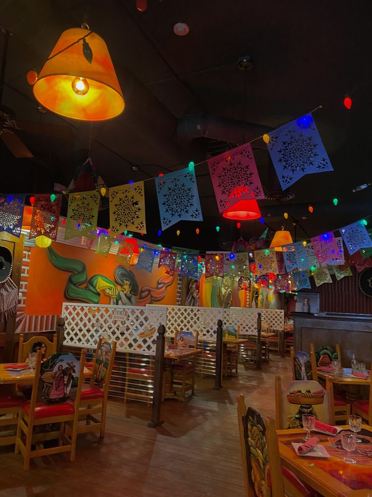 the interior of a restaurant with brightly colored lights hanging from the ceiling and decorated tables