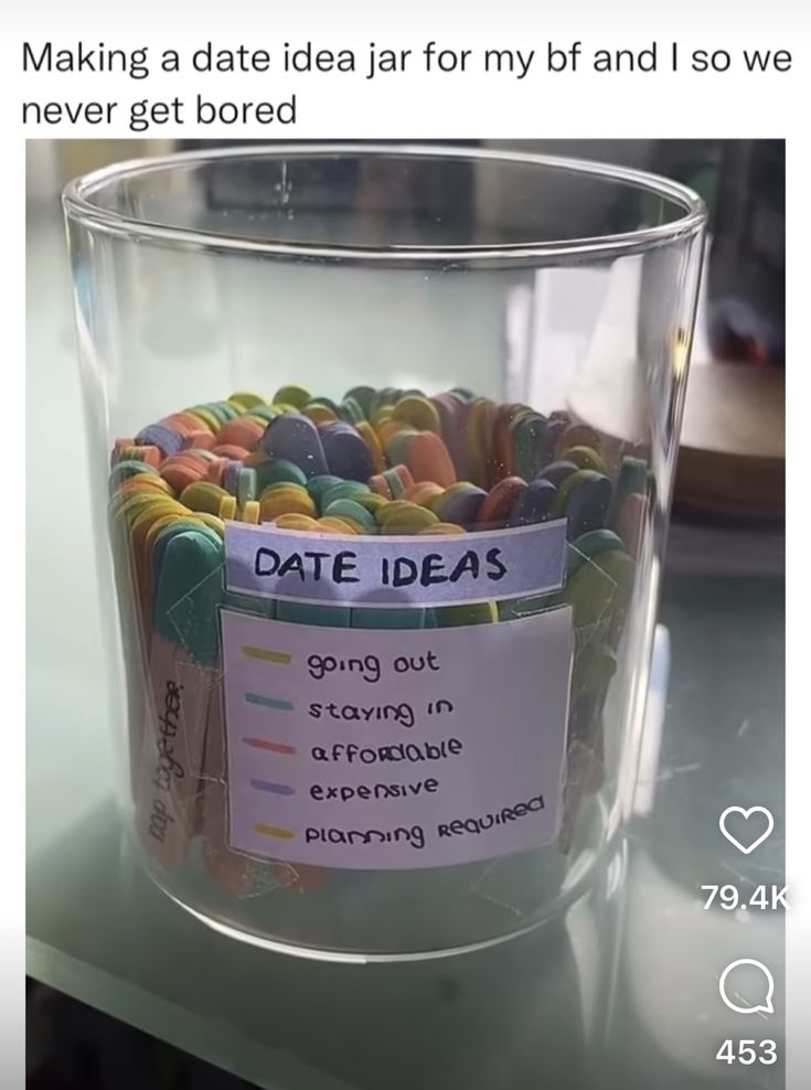 a glass jar filled with lots of candy on top of a table next to a sign that says date ideas