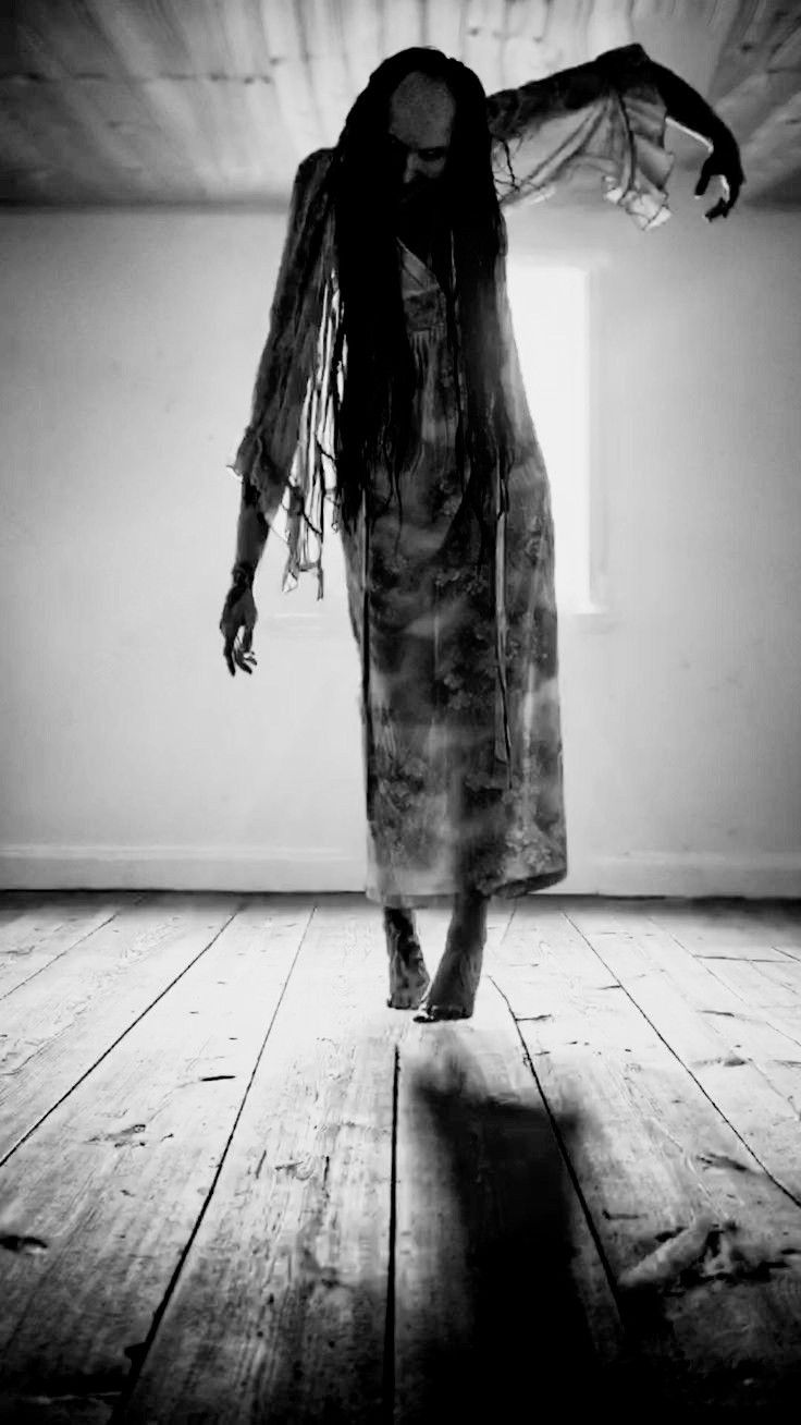 a woman with dreadlocks walking across a wooden floor in an empty room,