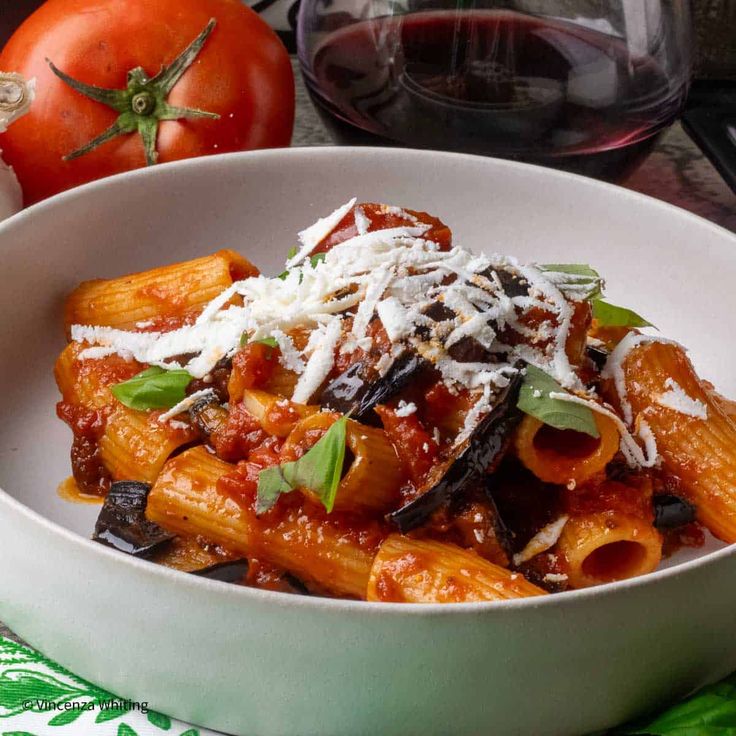 a white bowl filled with pasta covered in sauce and parmesan cheese on top