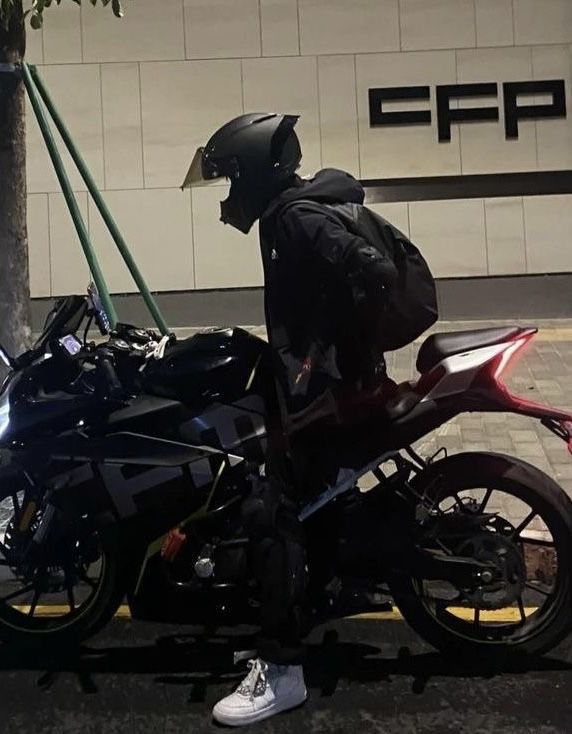 a person on a motorcycle parked in front of a building with a backpack strapped to it's back