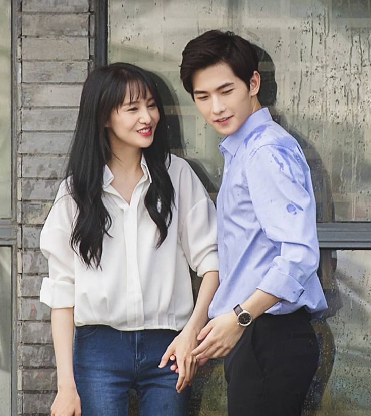 a man and woman standing next to each other near a wall with graffiti on it