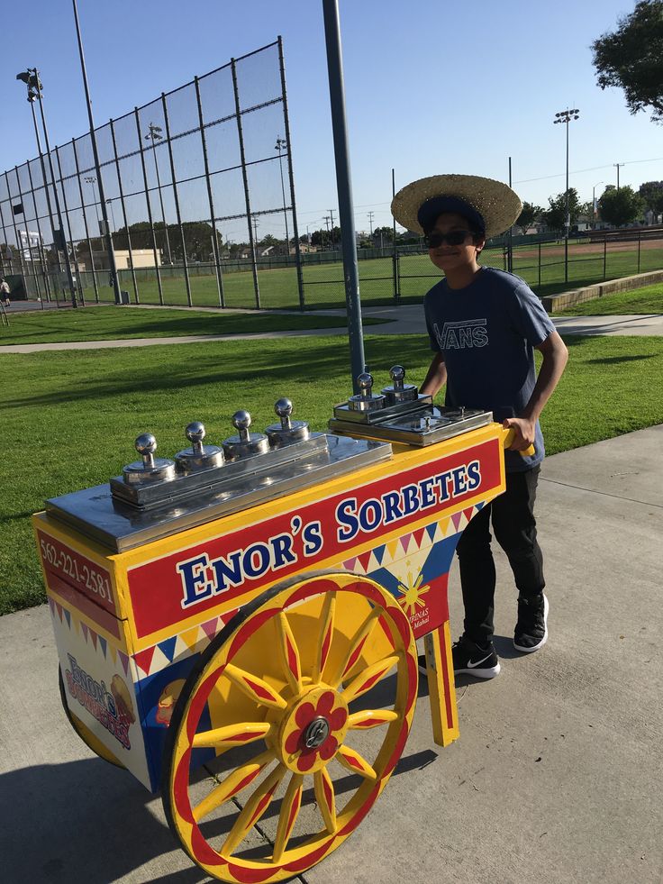 a man in a sombrero standing next to a cart with an ice cream machine on it