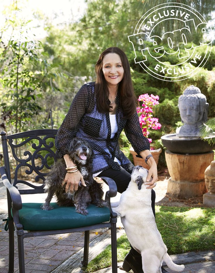 a woman sitting on a bench with two dogs