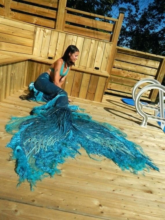 a woman is sitting on the deck with her peacock tail in front of her,