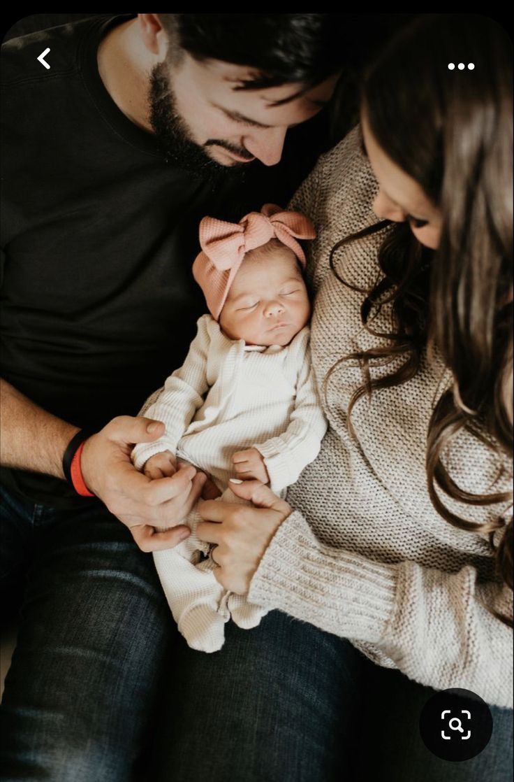 a man and woman holding a baby in their arms