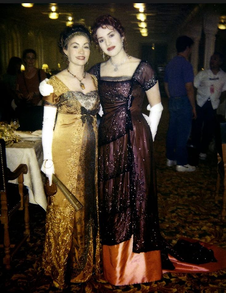 two women dressed in evening gowns pose for a photo at a formal dinner event