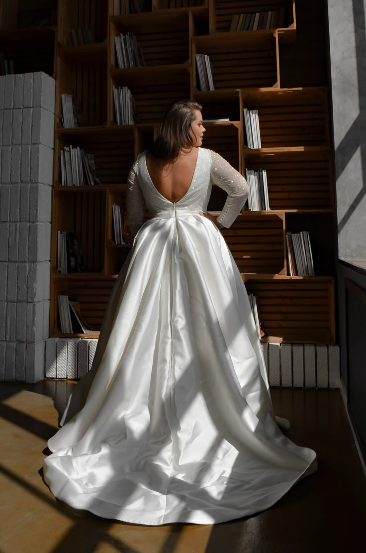 a woman standing in front of a bookshelf with her back turned to the camera