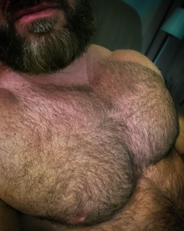 a hairy man with no shirt on laying down