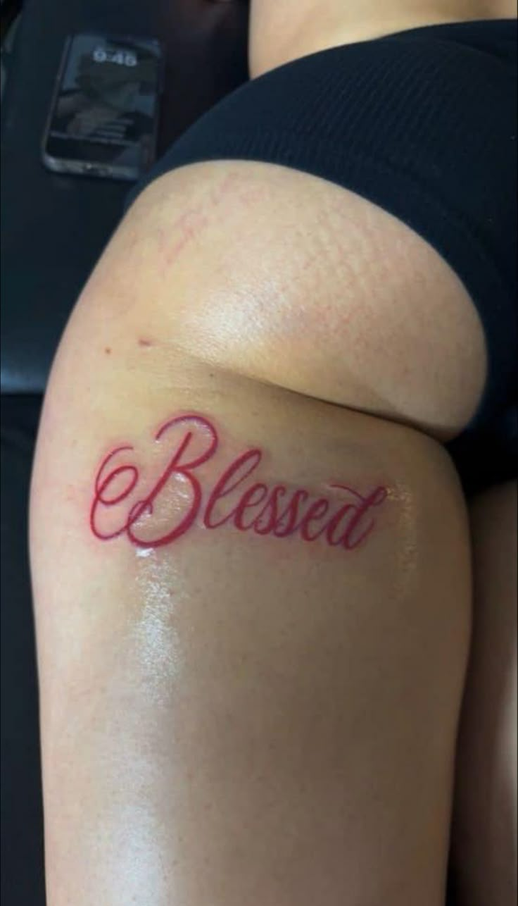 a woman with a tattoo on her thigh that says,'blessed'in cursive writing