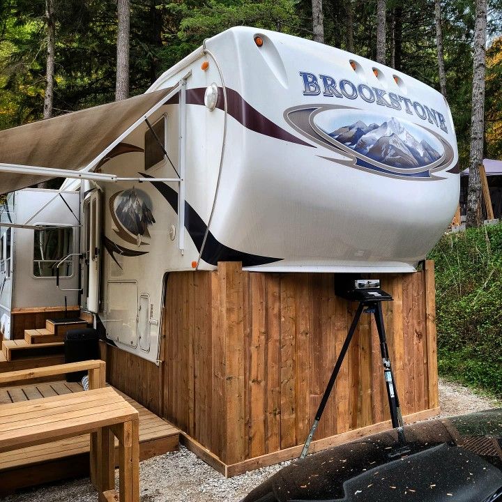 an rv parked in the woods next to a picnic table