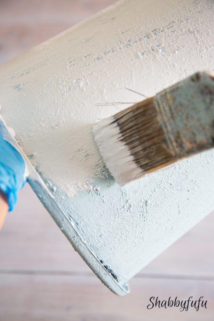 someone is painting a white wall with blue paint