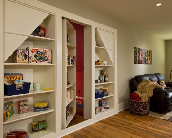 a living room filled with furniture and bookshelves next to a window on top of a hard wood floor