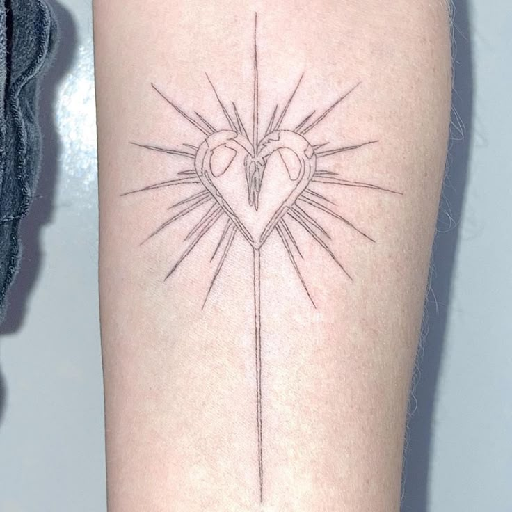 a tattoo on the arm of a woman with a cross and heart in the center