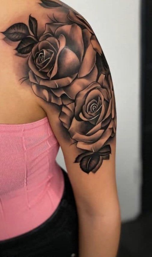 a woman's shoulder with black roses on her arm and the top half sleeve