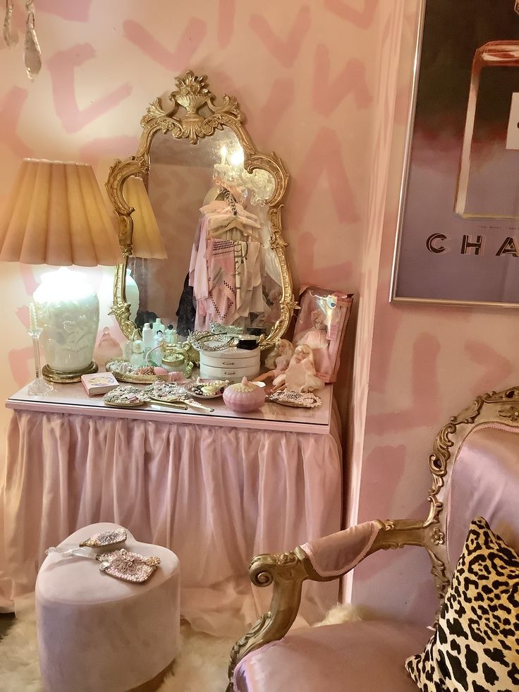 a pink and gold decorated room with an ornate chair, mirror, vanity and stool