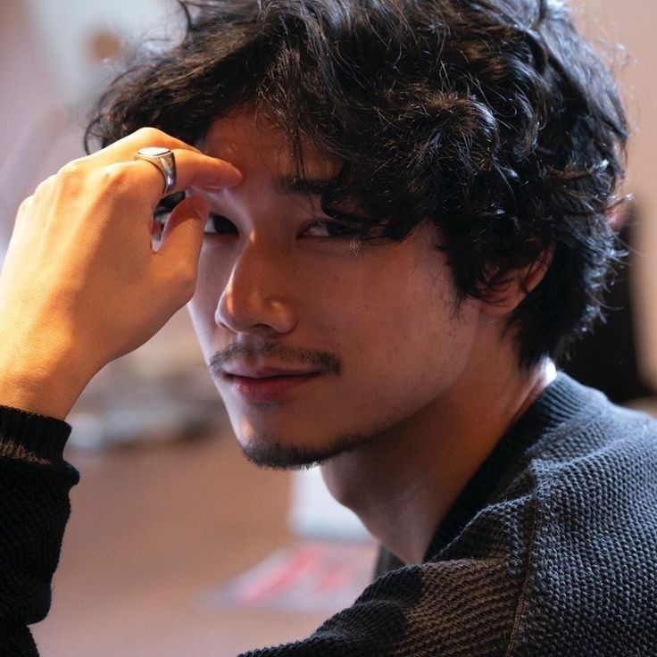 a close up of a person with a ring on his finger and wearing a sweater