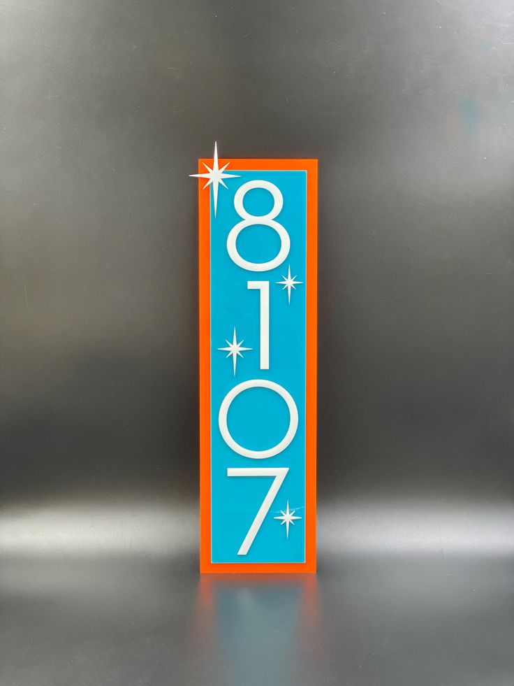 an orange and blue sign with the number 707 on it's side in front of a metallic background