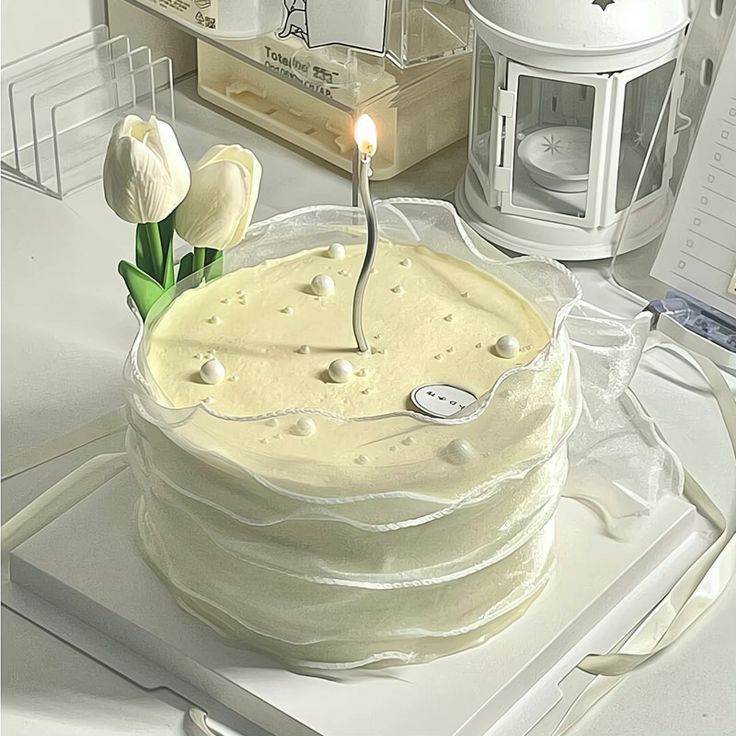 a white cake with a single candle on it sitting on a table next to other items