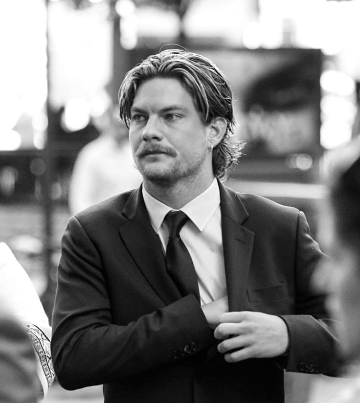 a man wearing a suit and tie standing in front of other people