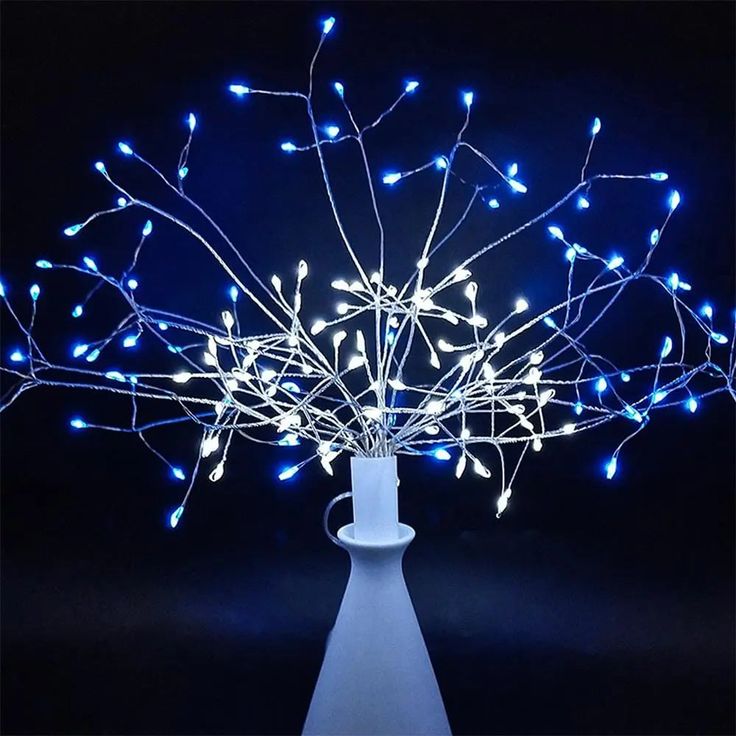 a white vase filled with blue lights on top of a table