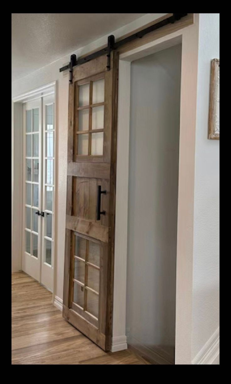 an open wooden door in the middle of a room with white walls and wood floors