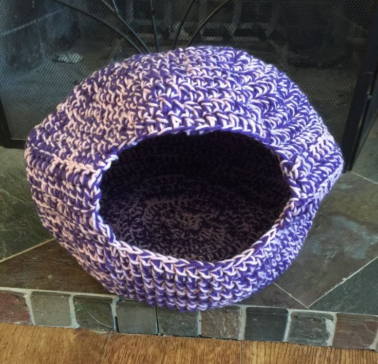 a purple and white basket sitting on top of a wooden floor next to a fire place