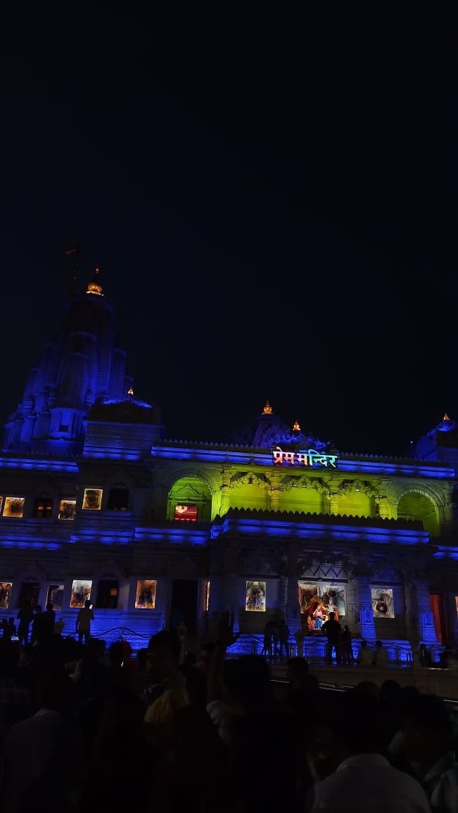 people are standing in front of a building lit up with blue and green lights at night