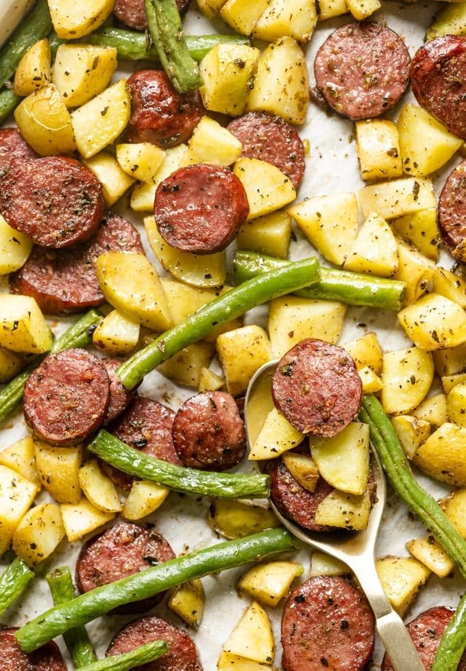 a sheet pan filled with potatoes, green beans and sausage