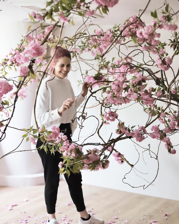 a woman standing in front of a tree with pink flowers