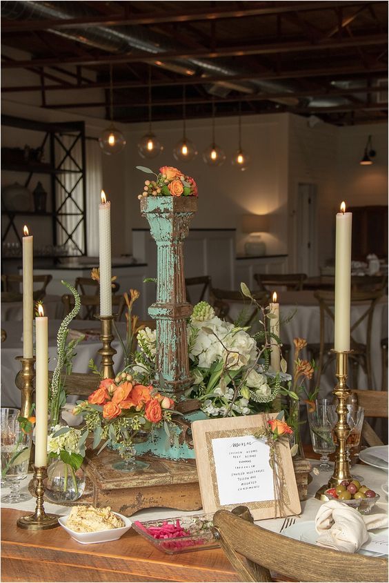 an arrangement of flowers and candles on a table