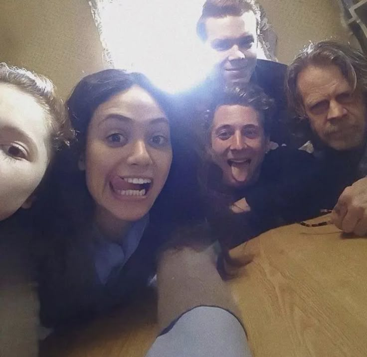 a group of people standing around a wooden table with their mouths open and one person sticking his tongue out