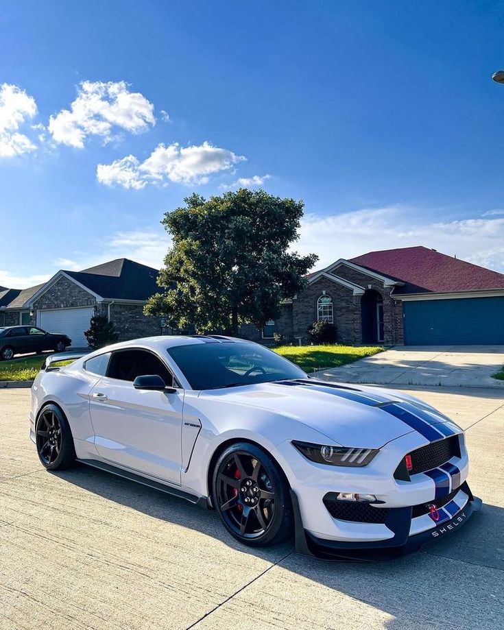 a white mustang parked in front of a house