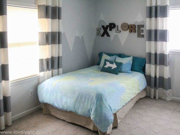 a bedroom decorated in blue and white with mountains on the wall above the bed, along with striped drapes