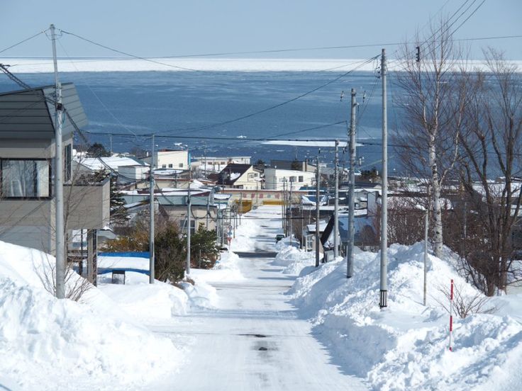 an empty street with snow on the ground and power lines in the air above it