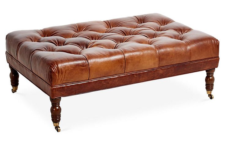 a brown leather ottoman sitting on top of a wooden table