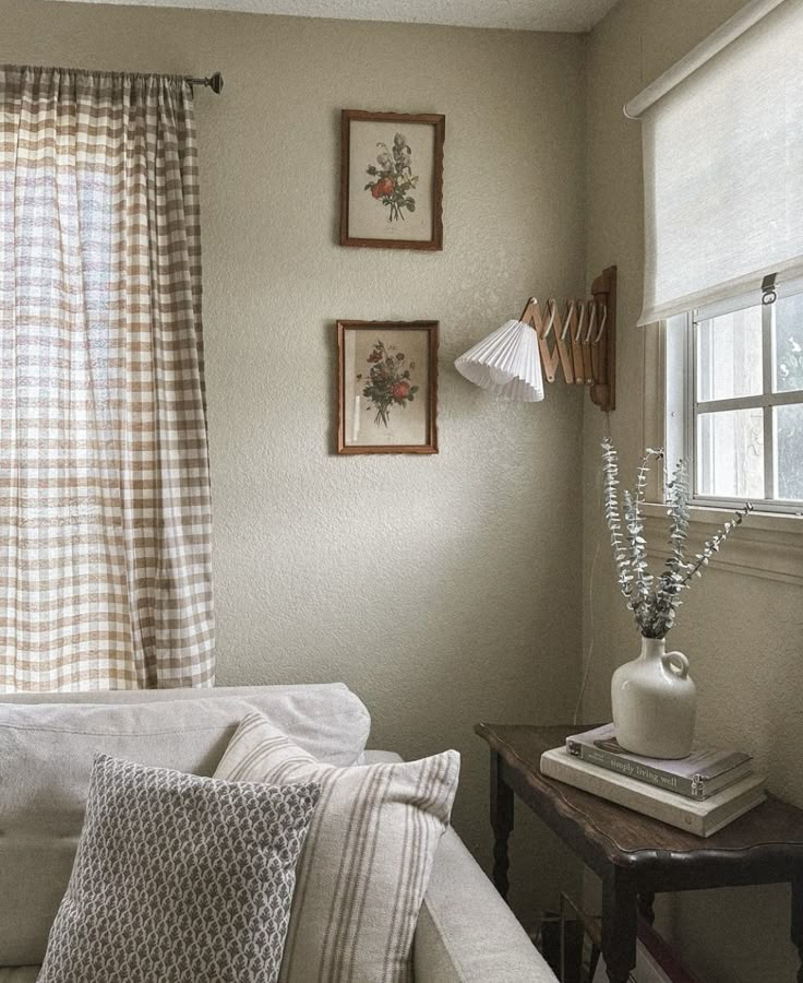 a living room with white couches and pictures on the wall next to window sill