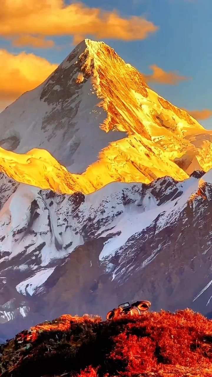 the mountain is covered in snow and has yellow light on it's peaks