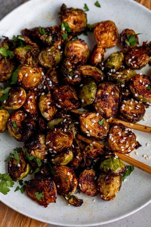 roasted brussel sprouts with sesame seeds and parsley on a white plate