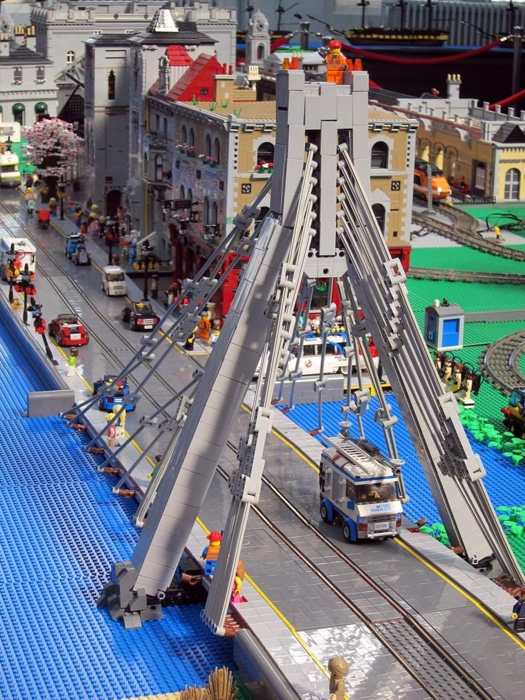 a bridge made out of legos is shown in the city with people and vehicles on it