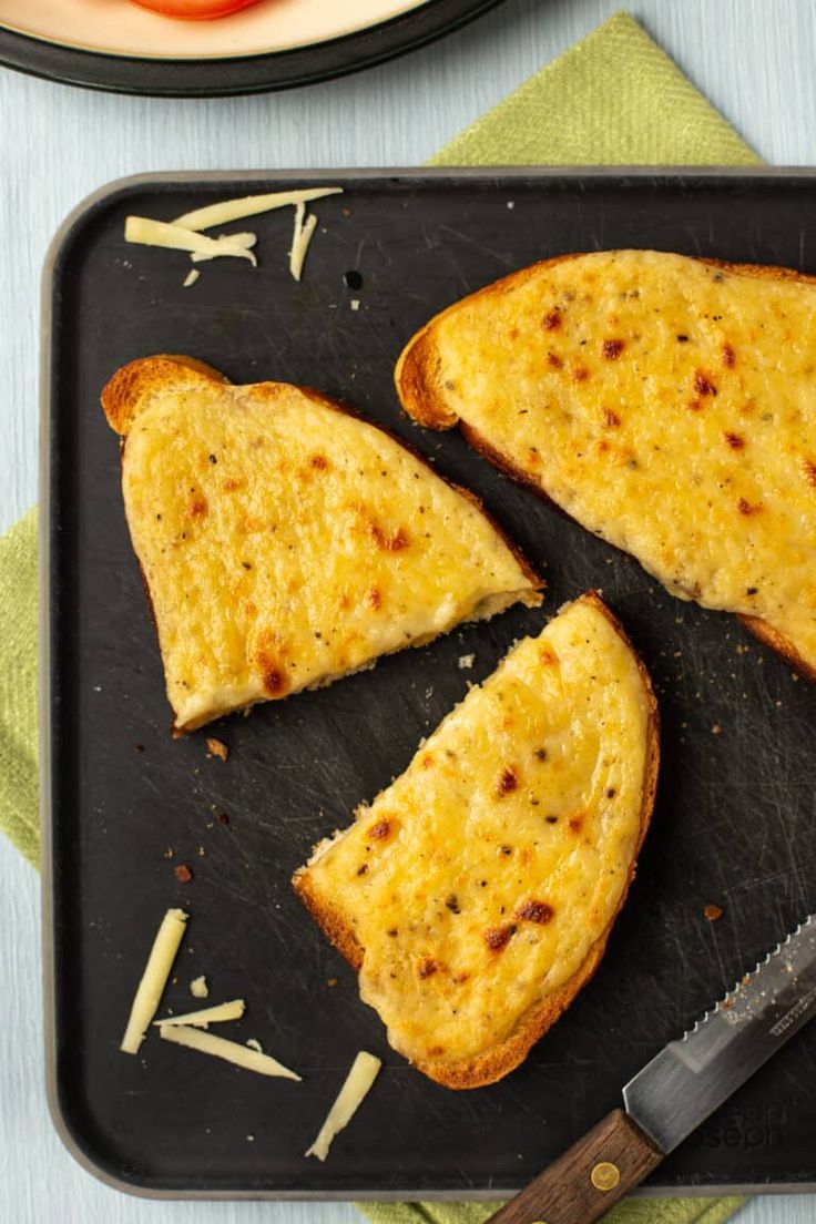 two pieces of toast on a black tray with a knife and fork next to it