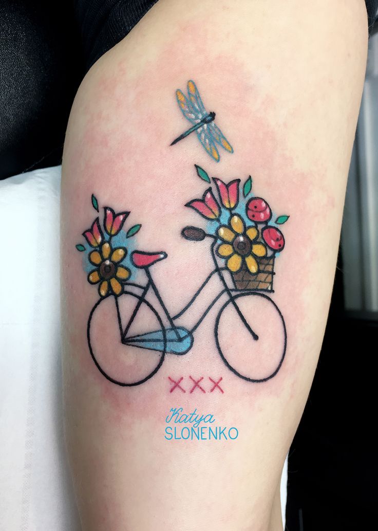 a woman's arm with flowers and a bicycle tattoo on the back of her leg