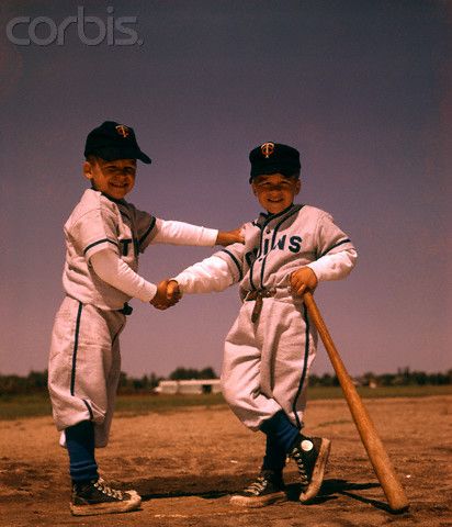 two young boys in baseball uniforms holding bats