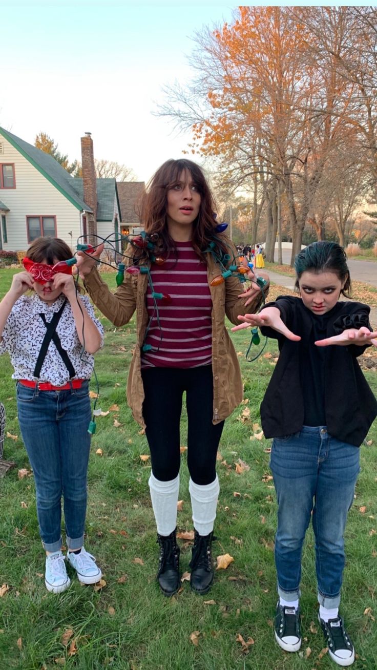 three young women standing in the grass with their hands out and one woman holding scissors