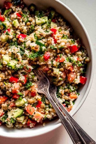 a bowl filled with rice and vegetables next to two spoons on top of a table