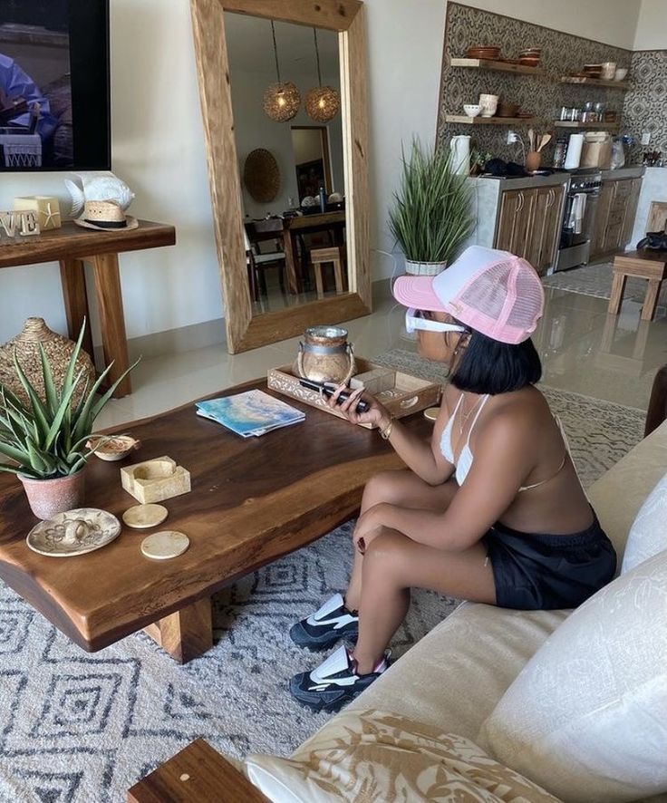 a woman sitting on top of a couch next to a wooden table in front of a tv